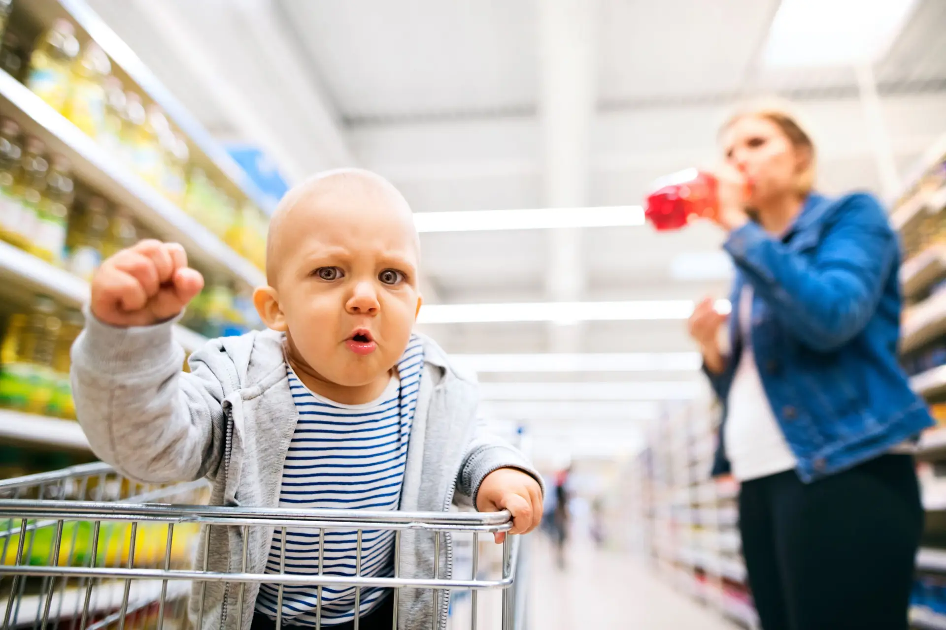 Young mother with her little baby boy at the supermarket, shopping.