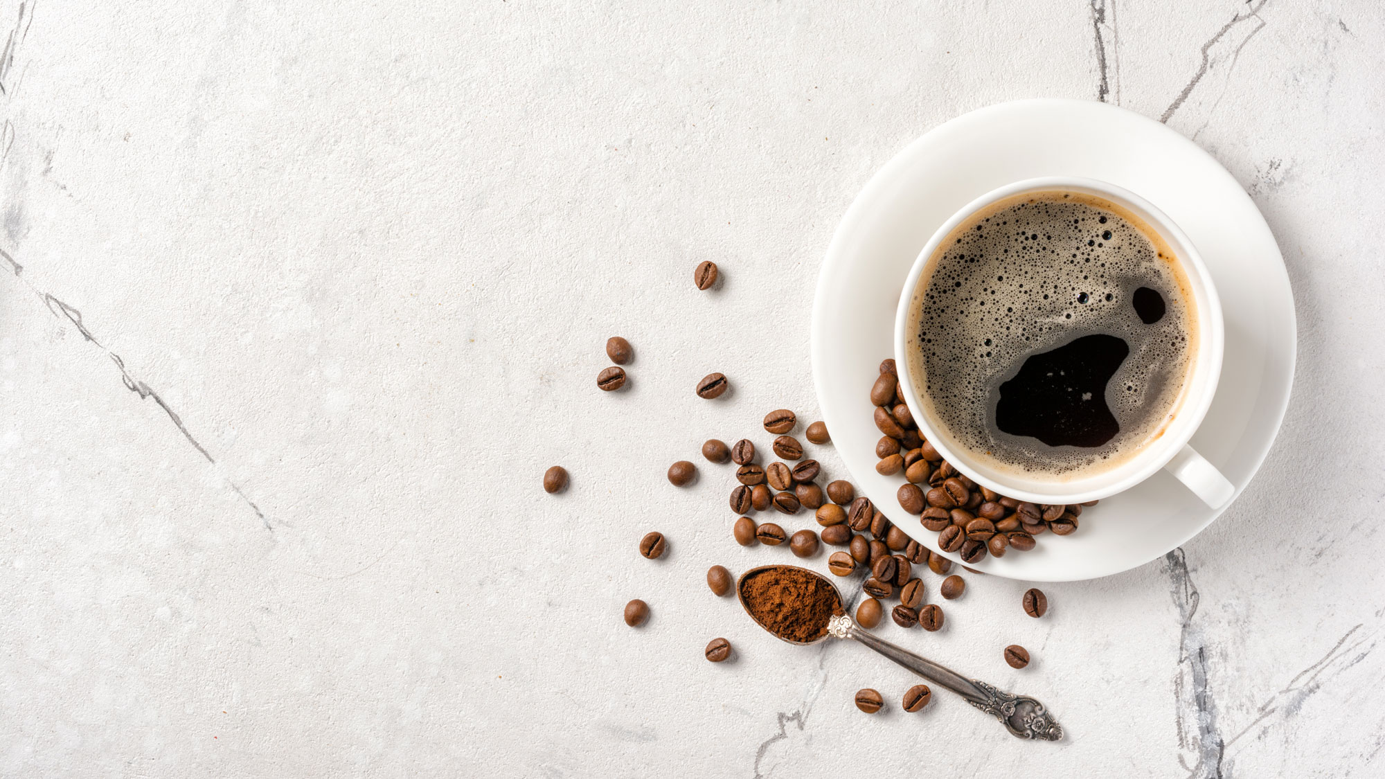 a cup of drip coffee with scattered coffee beans alongside